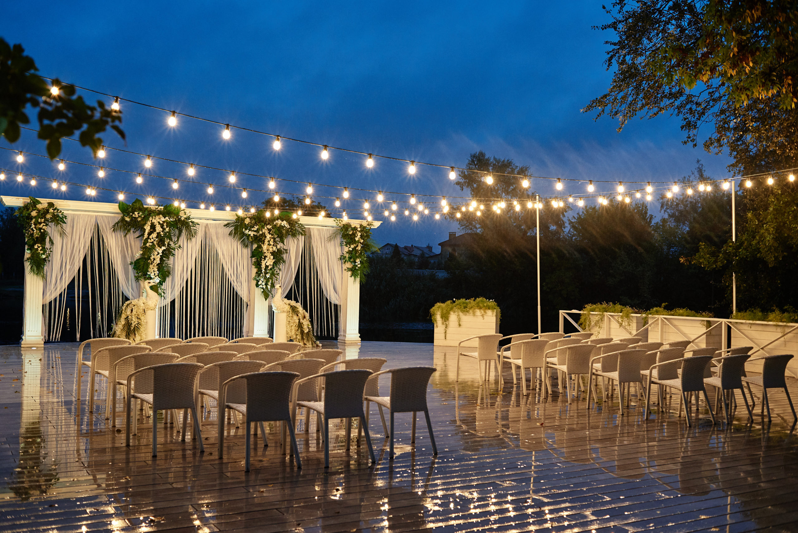 Night wedding ceremony with arch, orchid flowers, chairs and bul