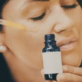 Close up of mid adult woman applying face serum on her face.