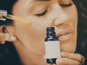 Close up of mid adult woman applying face serum on her face.