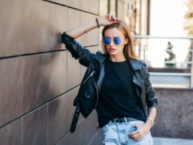 Girl wearing black t-shirt, glasses and leather jacket posing ag